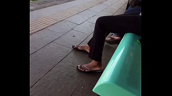 Tan lady playing with her slippers in the train platform